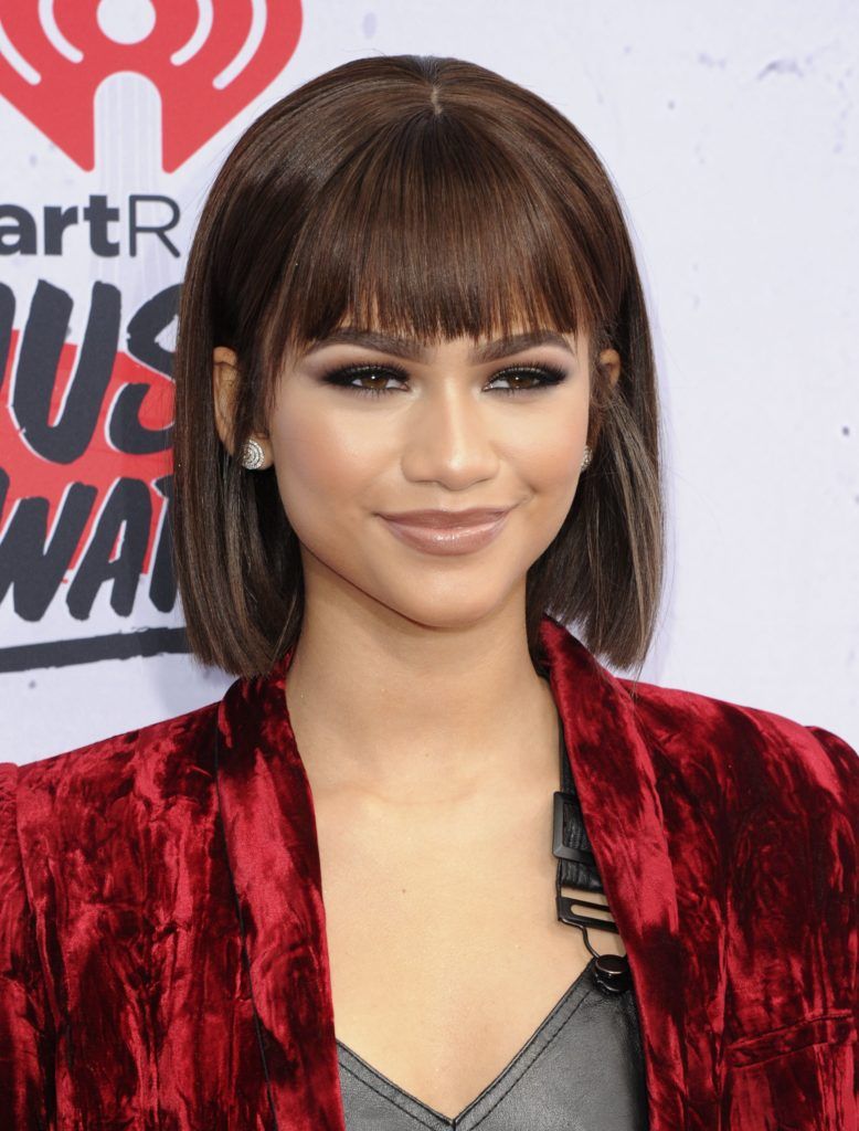 black hair bobs: close up shot of zendaya with scarface inspired bob hairstyle, wearing red velvet dress on the iHeartRadio Music Awards arrivals red carpet