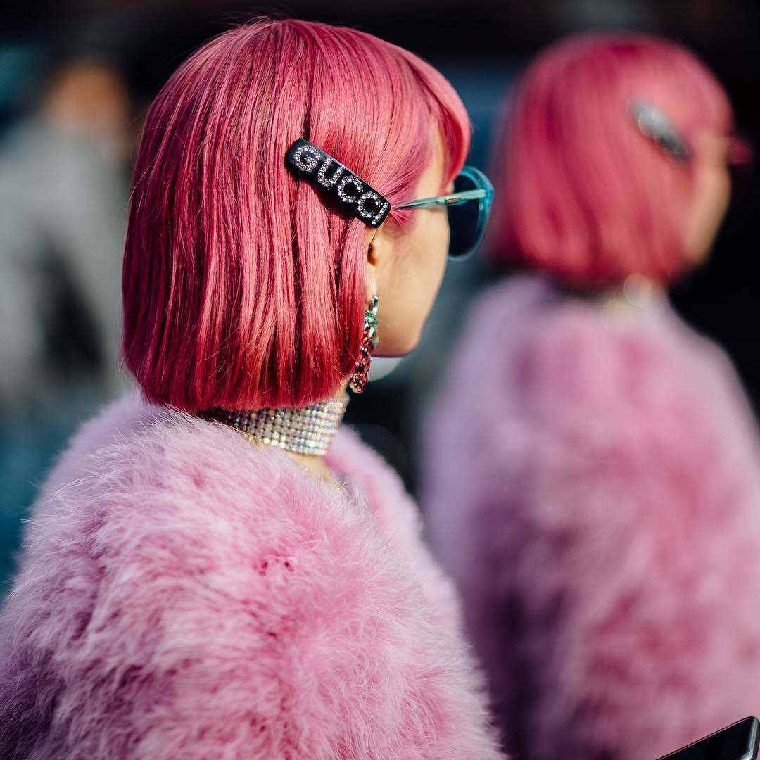 street style model wearing a pink fluffy fur coat and sunglasses with a Gucci hair slide in her short pink bob hairstyle