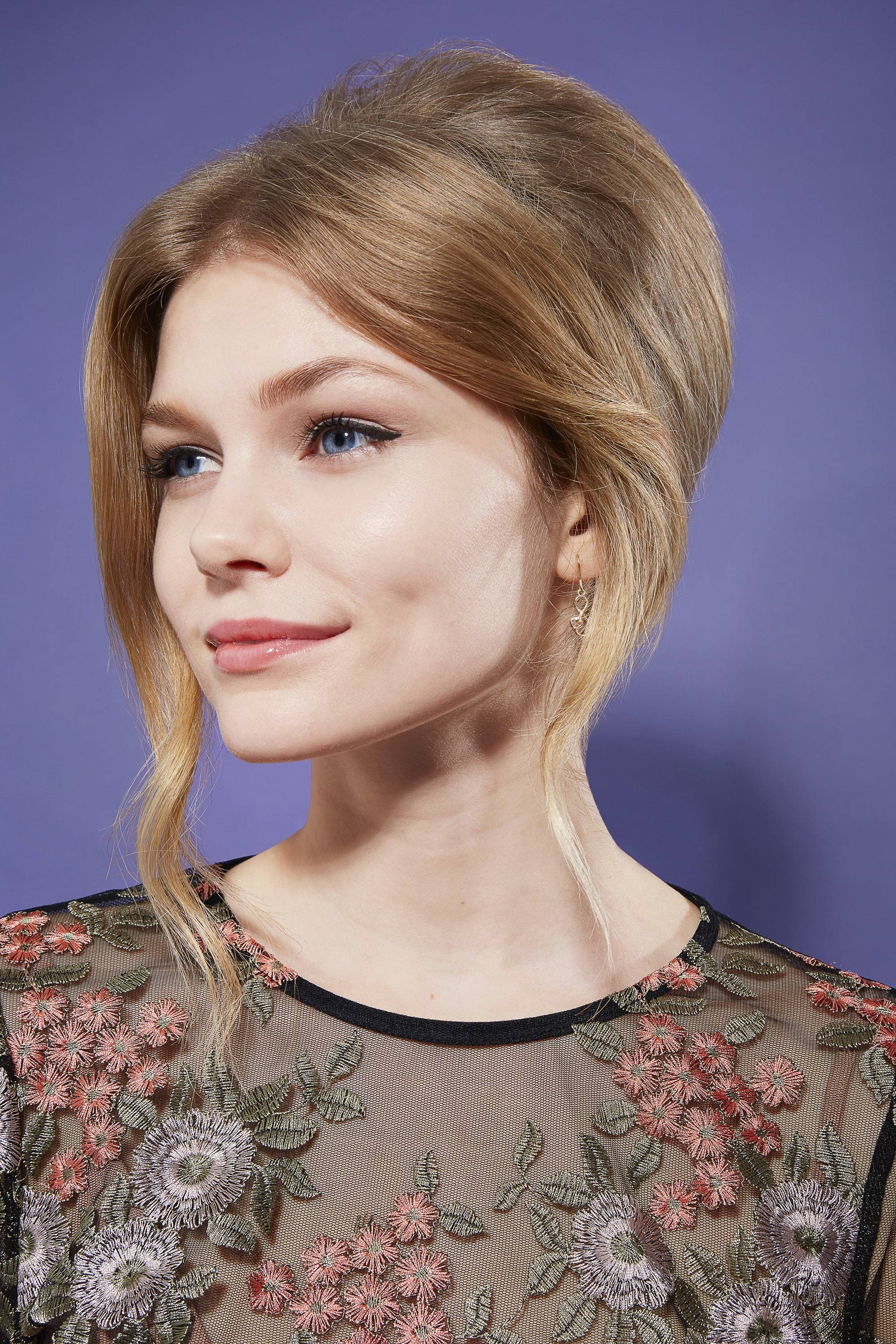 cute hairstyles for long hair: close up shot of woman with beehive updo, wearing floral top and posing in a studio