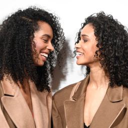 best shampoo for curly hair: close up shot of two women with curly hair, posing backstage at a fashion show
