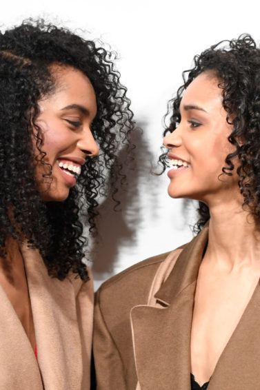 best shampoo for curly hair: close up shot of two women with curly hair, posing backstage at a fashion show