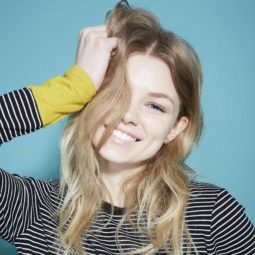 best shampoo for soft hair: close up shot of model in a studio with striped shirt, touching her blonde hair