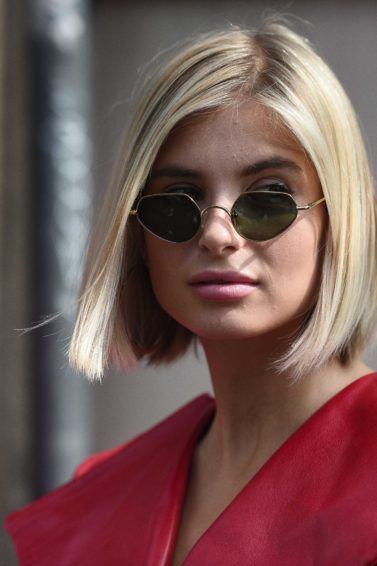 Milan Fashion Week street style: Close up shot of a woman with platinum blonde short hair, wearing sunglasses and a red dress