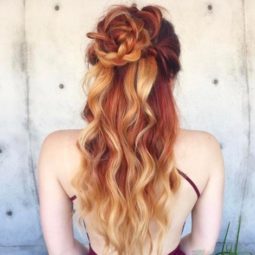 woman with ombre red to strawberry blonde long curly hair in a braided flower bun half-up style