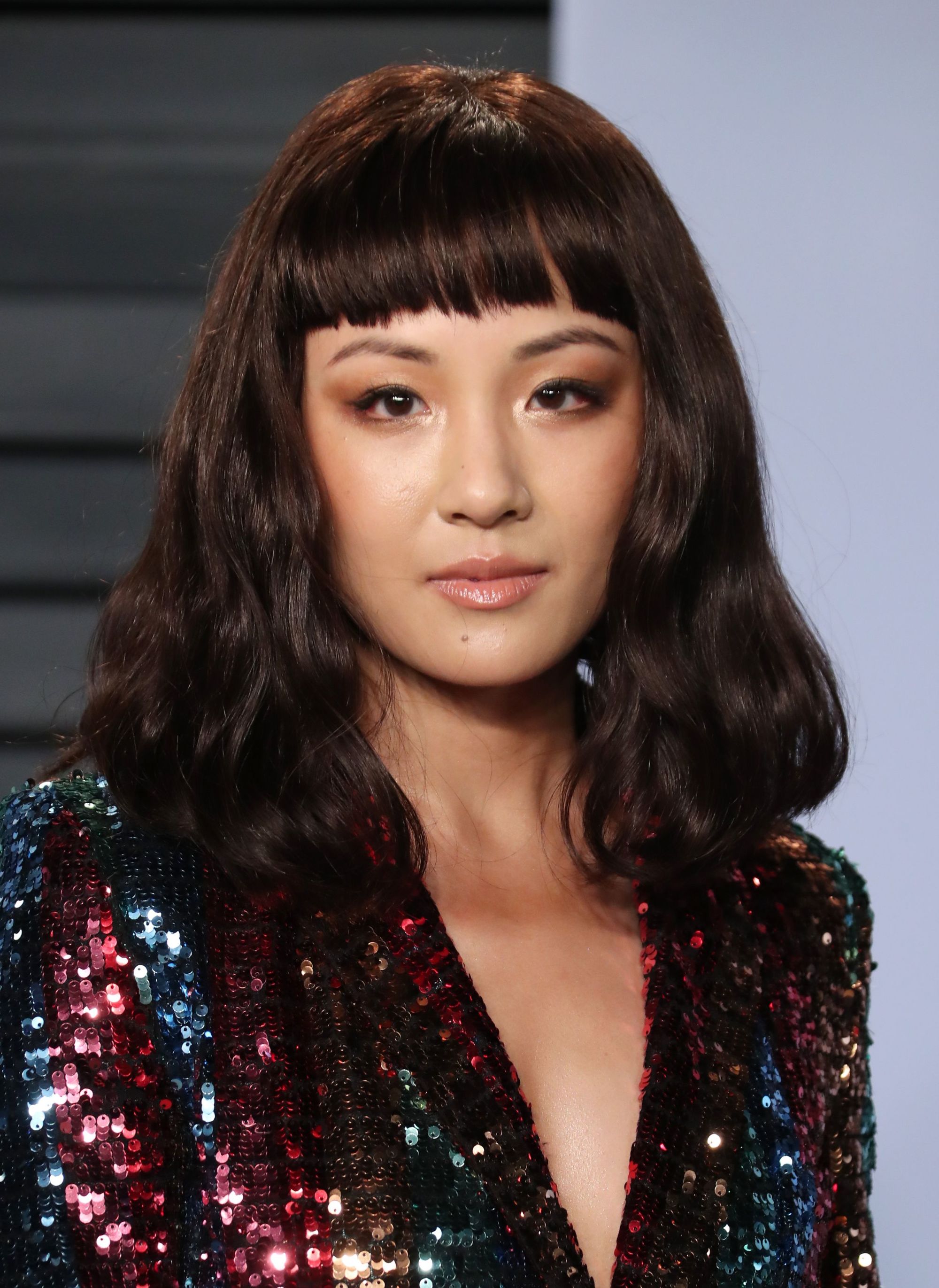 close up shot of constance wu on the red carpet with blunt cut bangs, wearing glittery dress on the oscars red carpet