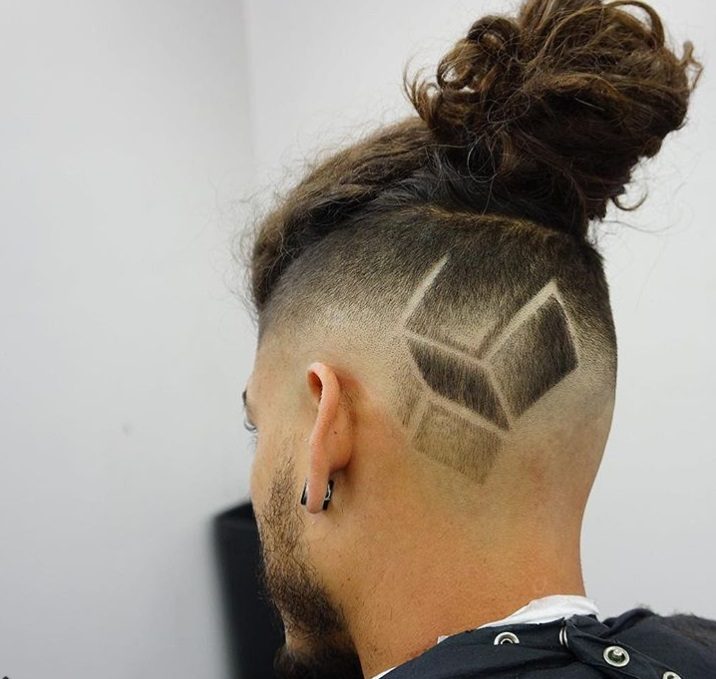 close up shot of man in a barber with messy man bun fade with abstract design on it