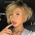 close up shot of woman with stacked bob hairstyle with side bangs, posing in a car