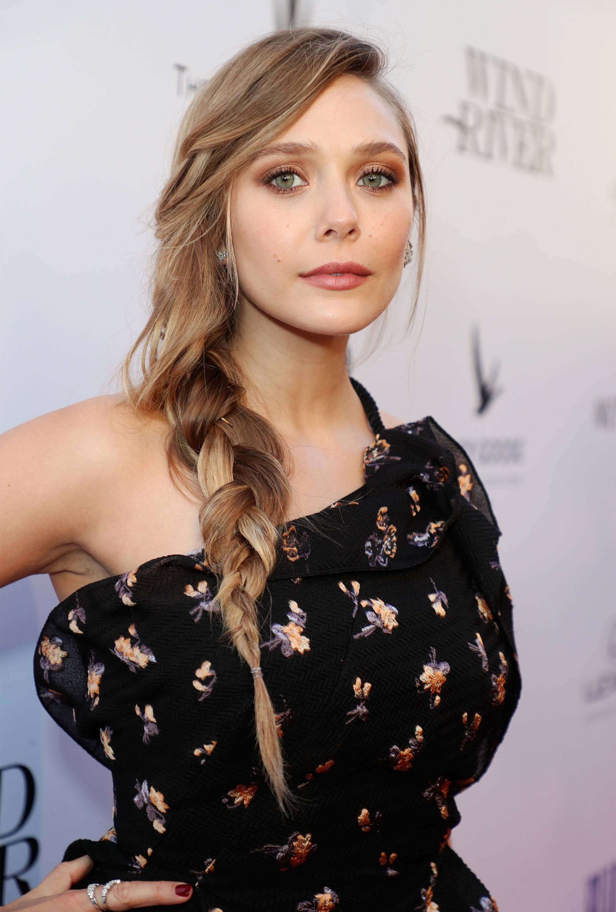 cute hairstyles for long hair for school: close up shot of woman with side braided ponytail, wearing black dress and posing
