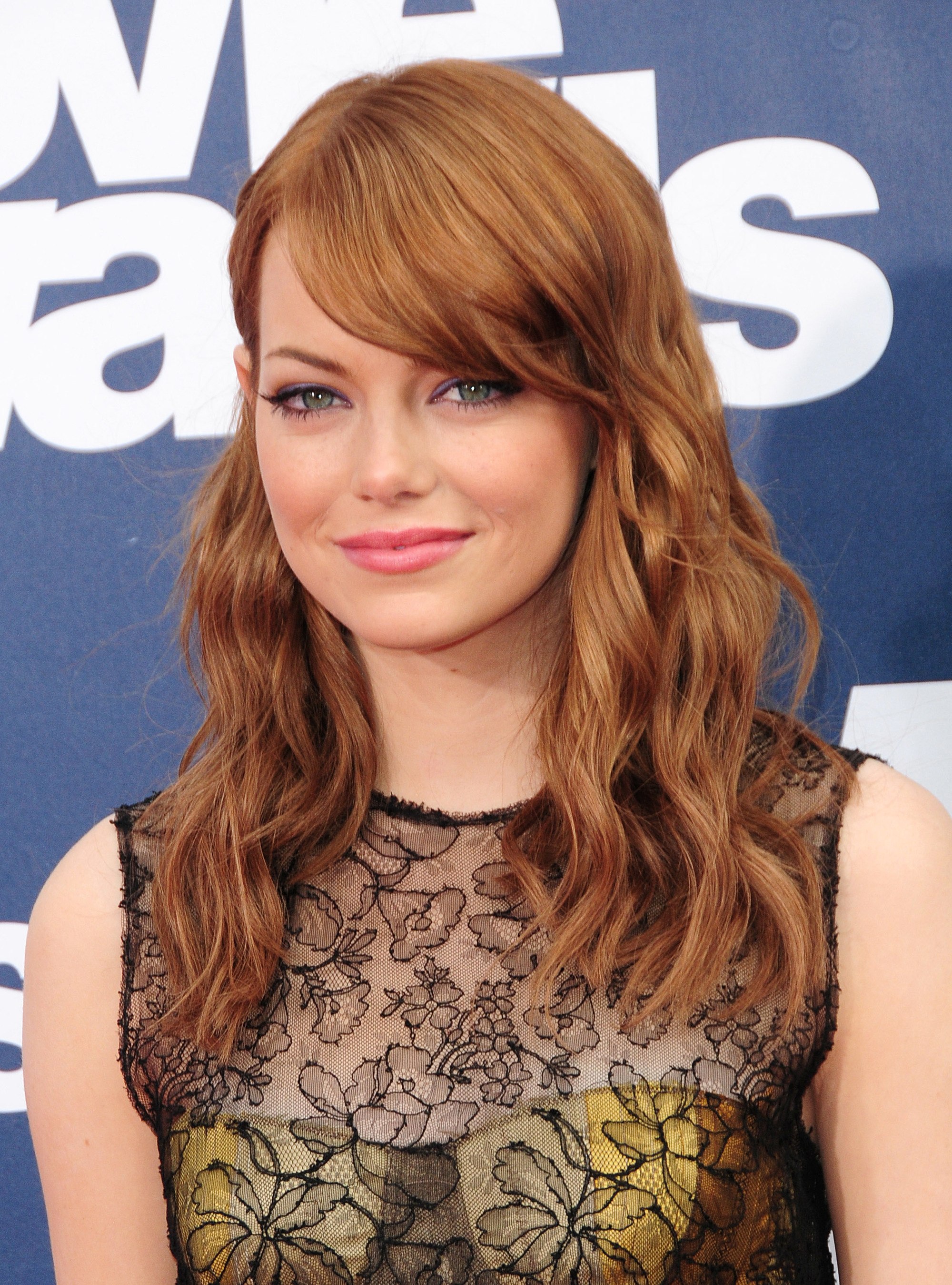 actress emma stone with wavy tousled mid length hair with swoop bangs