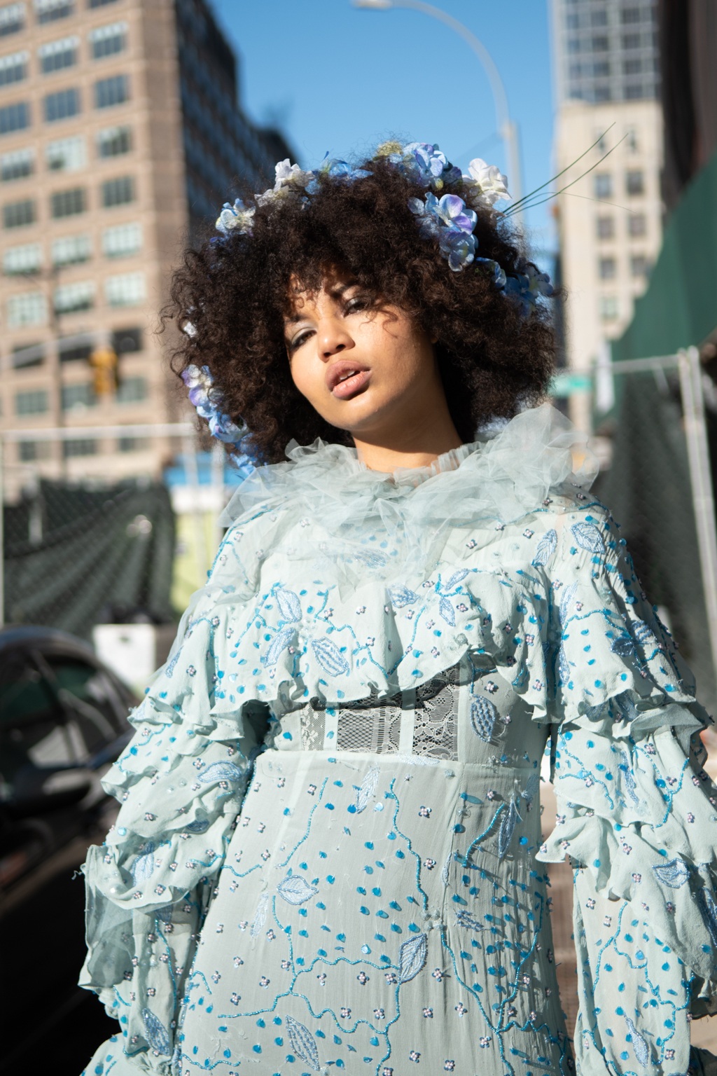 Spring haircuts: NYFW street style shot of a woman with afro hair with blue flowers in wearing a matching frilly blue floral dress