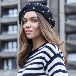 cute long hairstyles: close up shot of model with long wavy hair, wearing stripped top and posing outside with a pearl beret