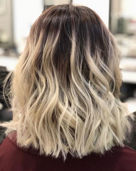 back view of medium length wavy blonde hair with dark roots