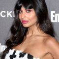 Sexy hairstyles for long hair: Jameela Jamil with dark brown wavy hair with retro inspired split bangs, wearing a monochrome patterned strapless dress