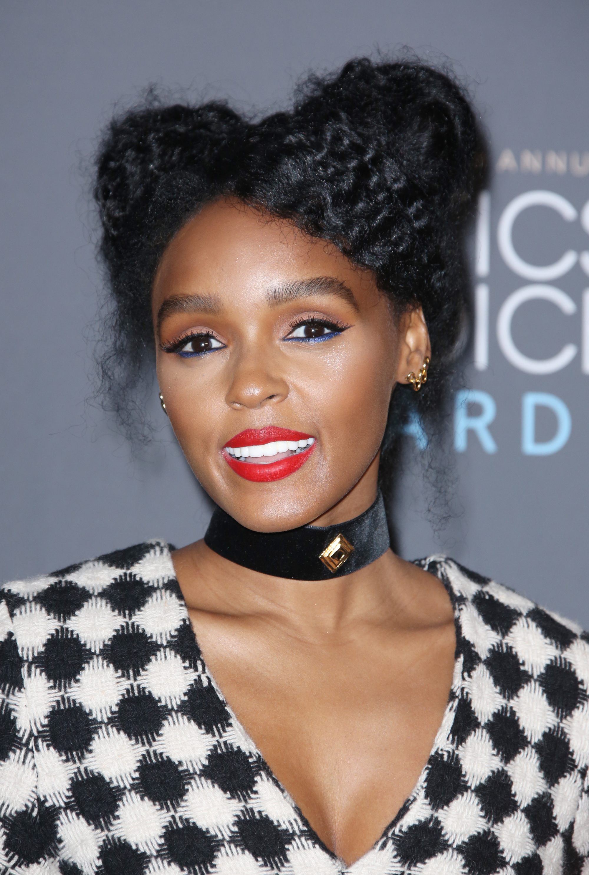cute long hairstyles: close up shot of janelle monae with space buns hairstyle, wearing checked top and choker