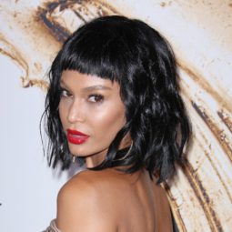 black hairstyles with bangs: close up shot of joan smalls with micro fringe and short curly hair, wearing red lipstick and golden dress on the CFDA awards red carpet