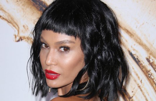 black hairstyles with bangs: close up shot of joan smalls with micro fringe and short curly hair, wearing red lipstick and golden dress on the CFDA awards red carpet