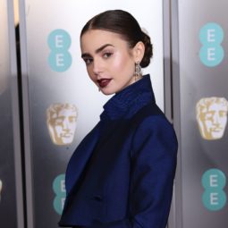 BAFTAs hairstyles: Lily Collins with dark brown hair in smooth low bun with dark lipstick on red carpet 2019.