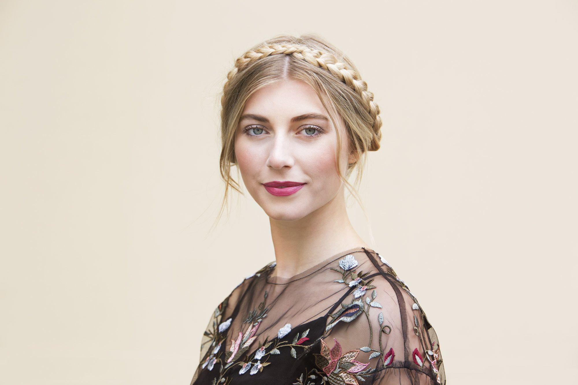 close up shot of woman with milkmaid braid updo, wearing floral dress and posing in a studio