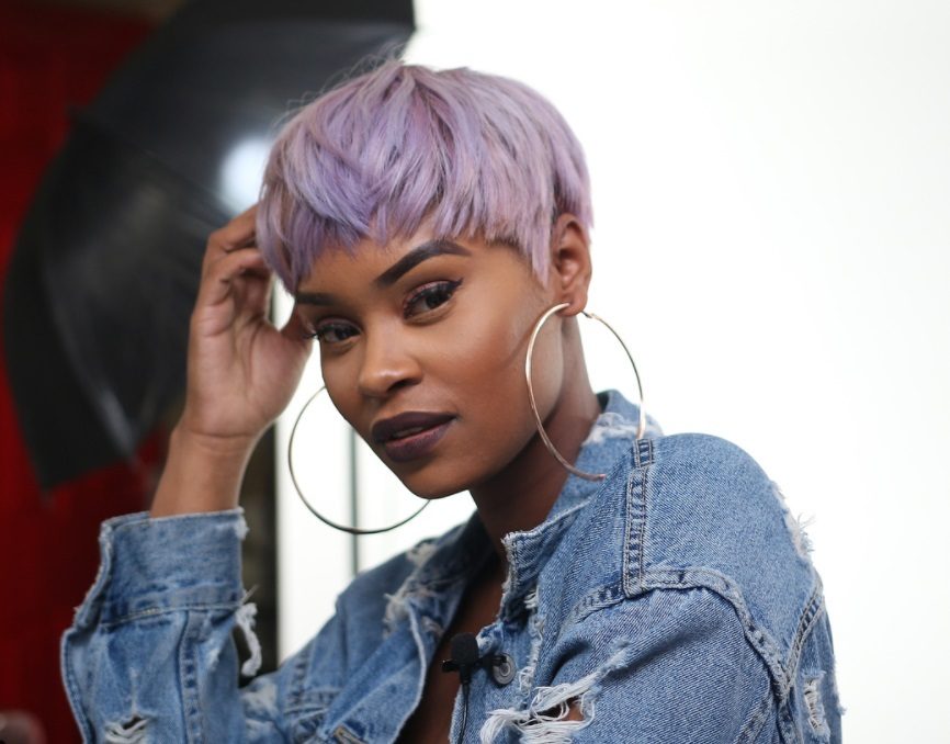 short weave hairstyles: close up shot of woman with short textured pixie haircut, wearing denim and posing outside