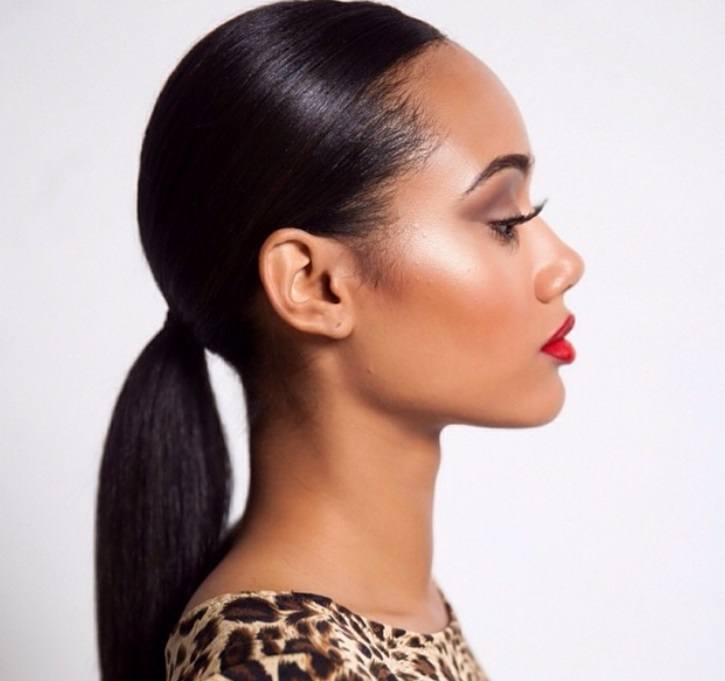 Night out hairstyles: Woman with long, dark brown relaxed hair styled into slick ponytail, wearing red lipstick and leopard print top