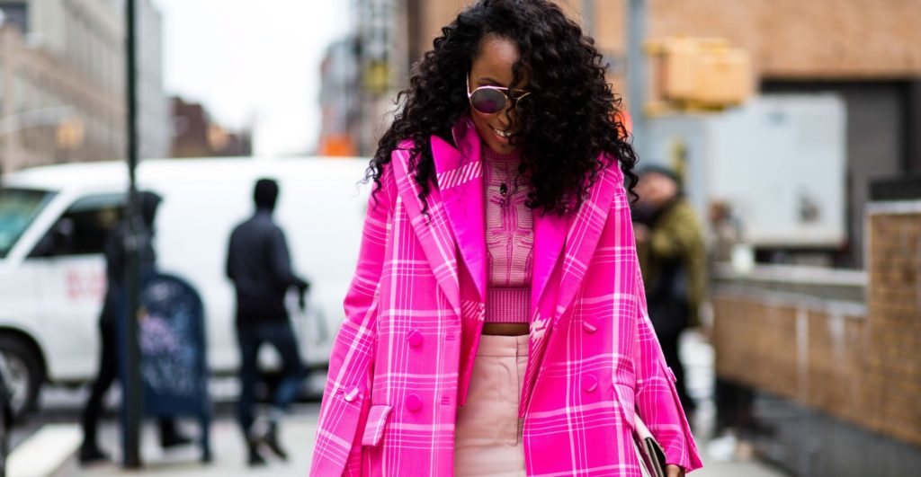 Black girl with curly hair walking outside fashion week show