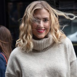 Hair hacks for winter: Shot of a woman with beige turtleneck, with medium golden blonde curly hair posing for street style picture