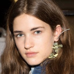 Hair thickening shampoo: Close-up of a brunette model with thick medium length hair tucked behind her ears, backstage at acne FW18 runway show