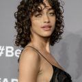 alanna arrington with shoulder-length curly brown hair with curly fringe wearing a black camisole dress