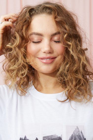 Woman touching her curly blonde hair