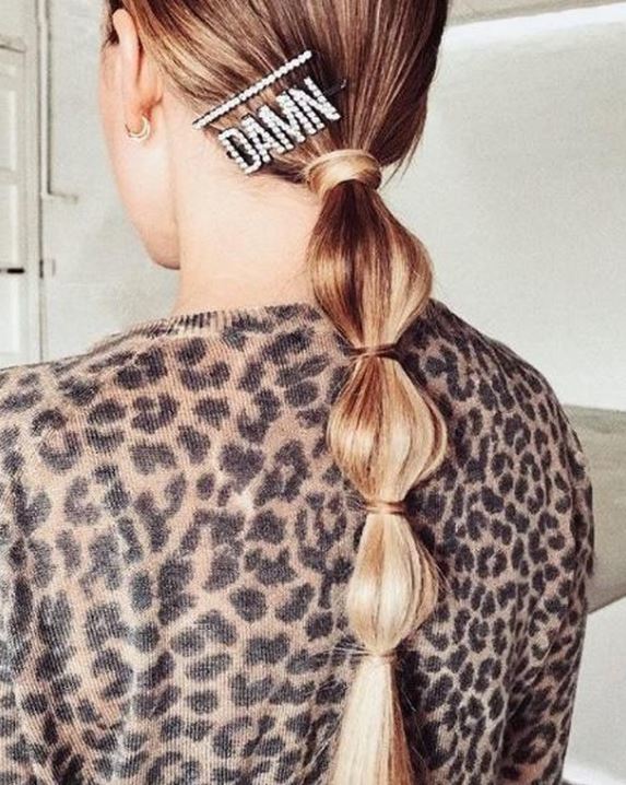 Second day hair: Woman with long golden blonde straight hair in low bubble ponytail with jewelled hair clip.