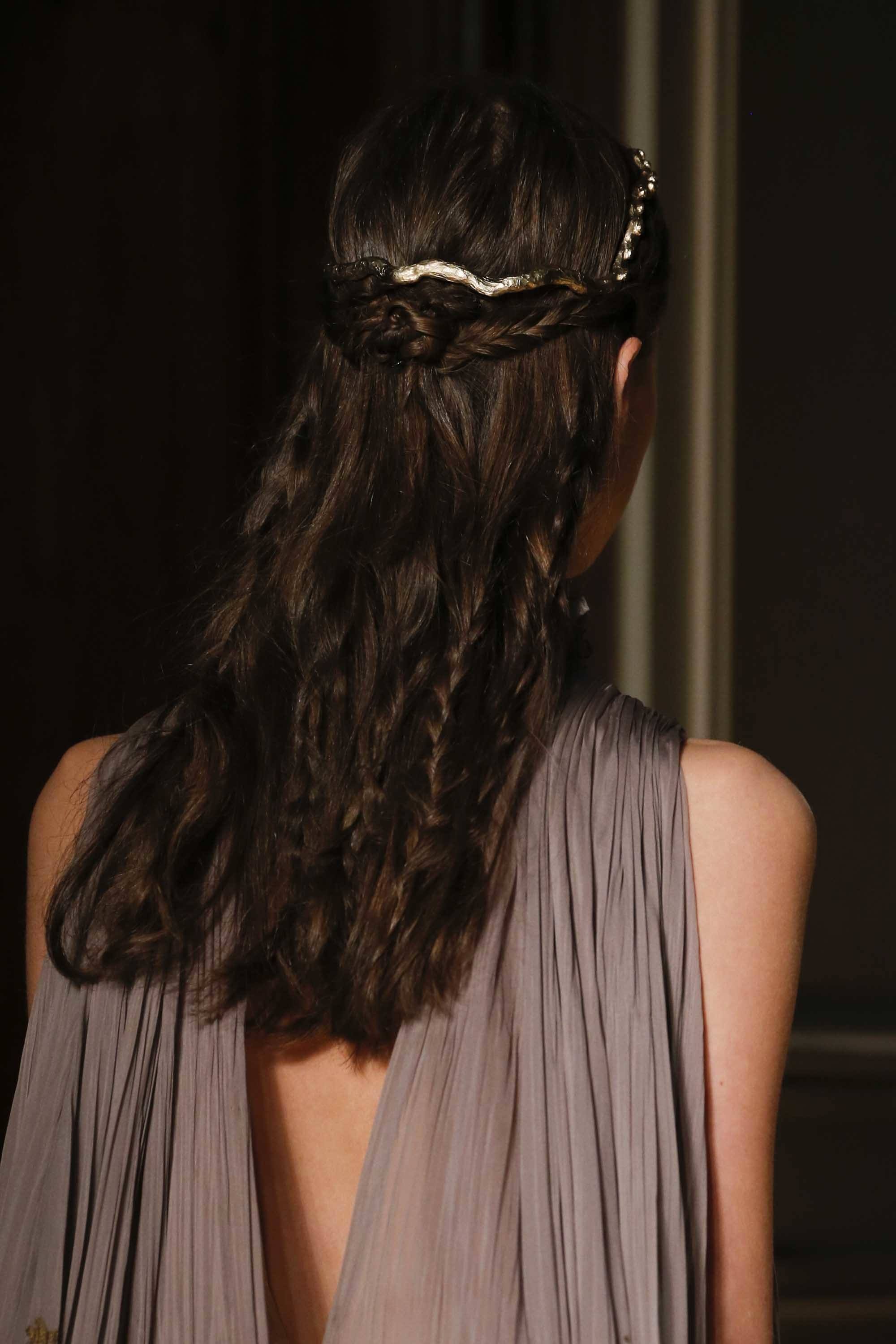 close up shot of model with half up half down rose braid, with hidden plaits, wearing silver and walking on the runway