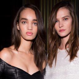 Frizzy hair products guide: Two models with brown hair that has been styled into smooth, polished waves, wearing Balmain clothing backstage