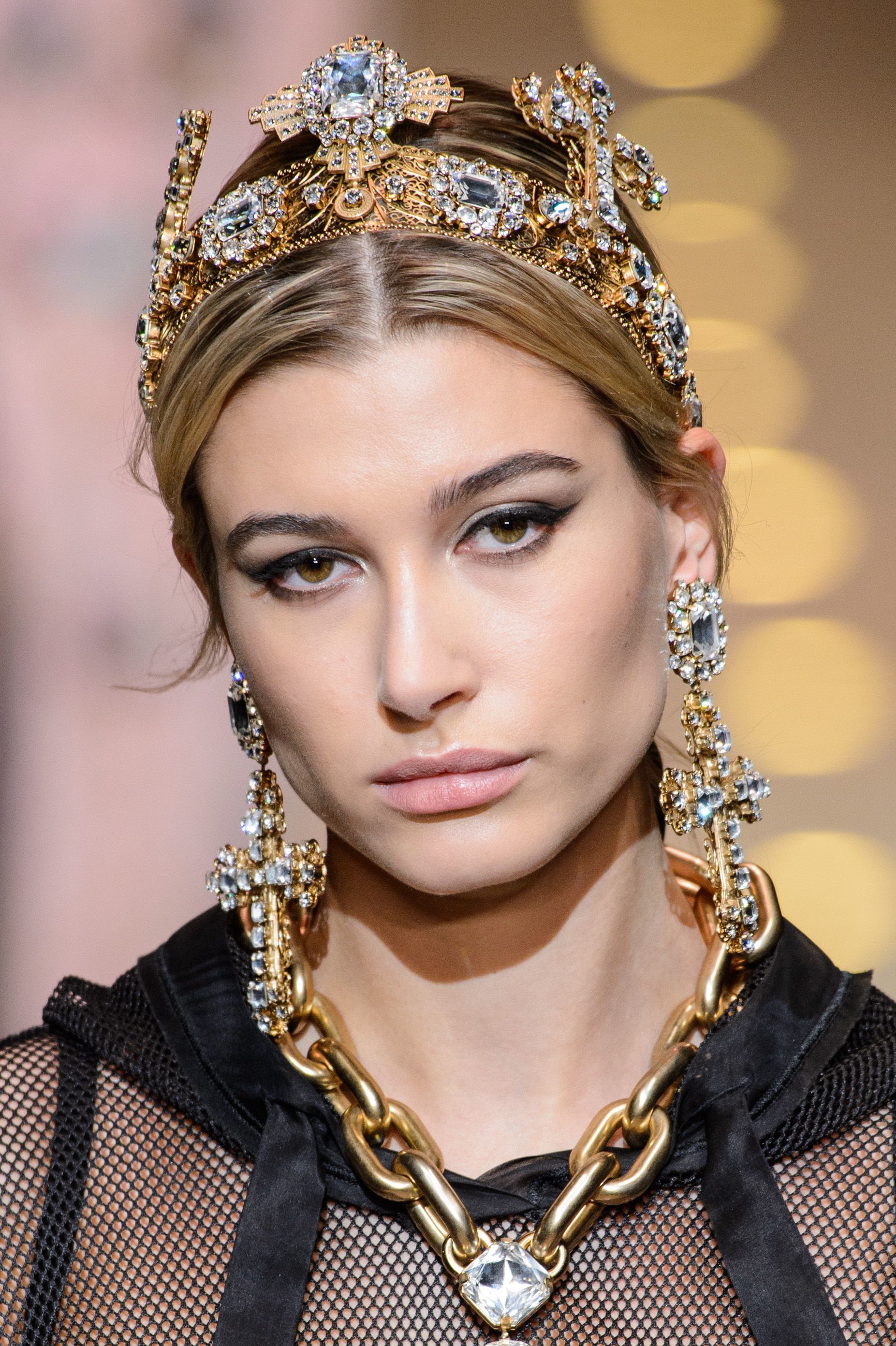 close up shot of hailey baldwin with a tiara hair accessory, wearing black lace, gold necklace and walking on the runway
