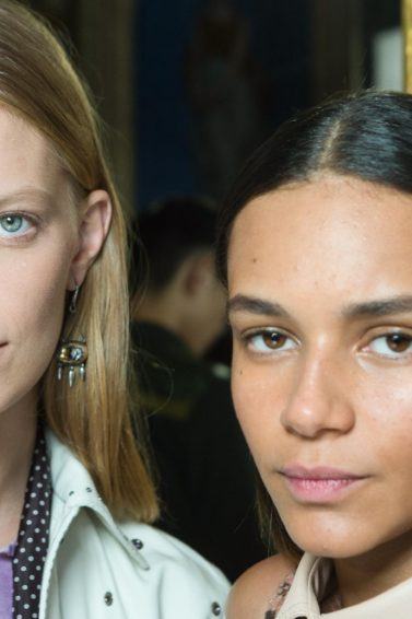 Two models backstage at the Bottega Veneta show with smooth, straight hair staring into the camera