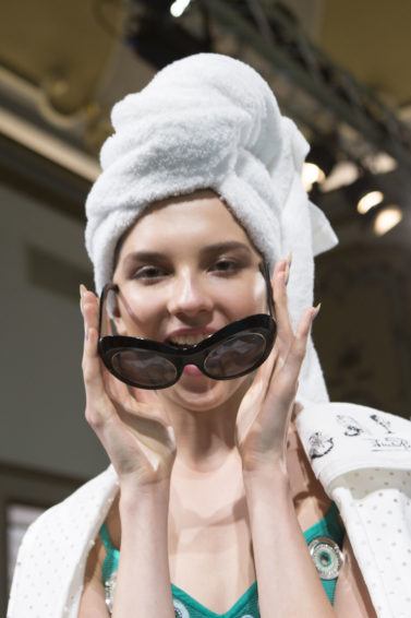 hair restoration shampoo guide: close up shot of model with printed towel on her head, wearing matching bathrobe, posing backstage at the emillio pucci SS18 show