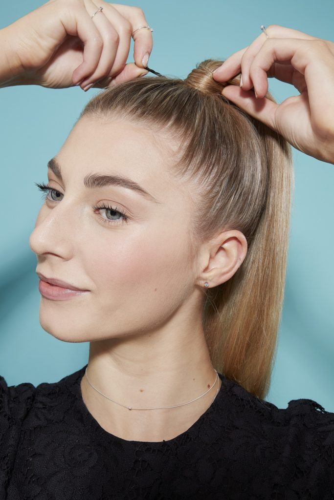 Blonde woman creating high ponytail hairstyle