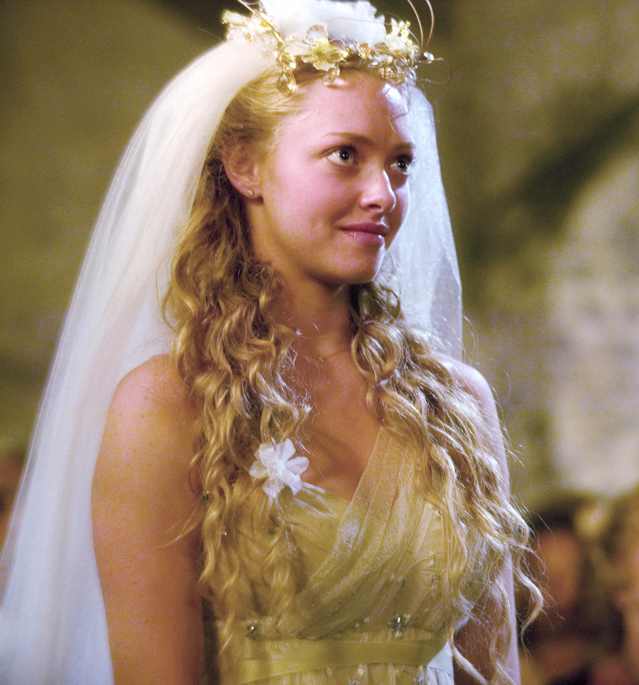 close up shot of amanda seyfried as sophie, with half up curly hairstyle, viel and flowers, on the set of mamma mia