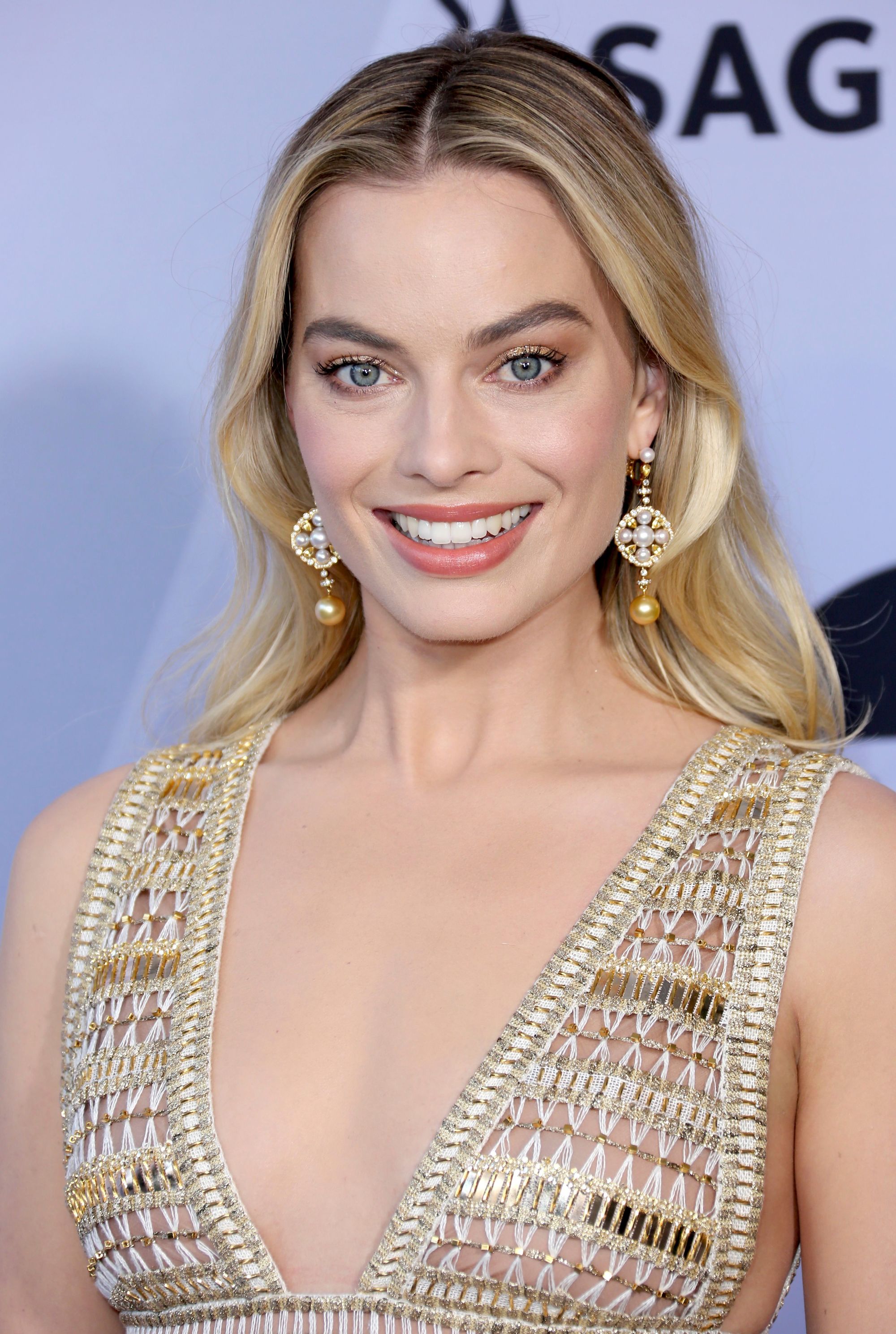 International Women's Day hair icons: Margot Robbie with long golden blonde hair loosely waved, wearing a golden dress on the red carpet