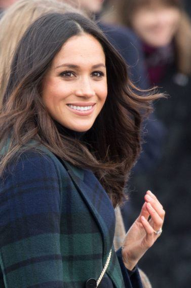 texturising hair products guide: close up shot of meghan markle with tousled hair, wearing green and black jacket and posing outside