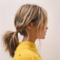 Second day hair: Laura Whitmore with blonde highlighted hair in a low ponytail with jewelled hair clip wearing a yellow jumper.