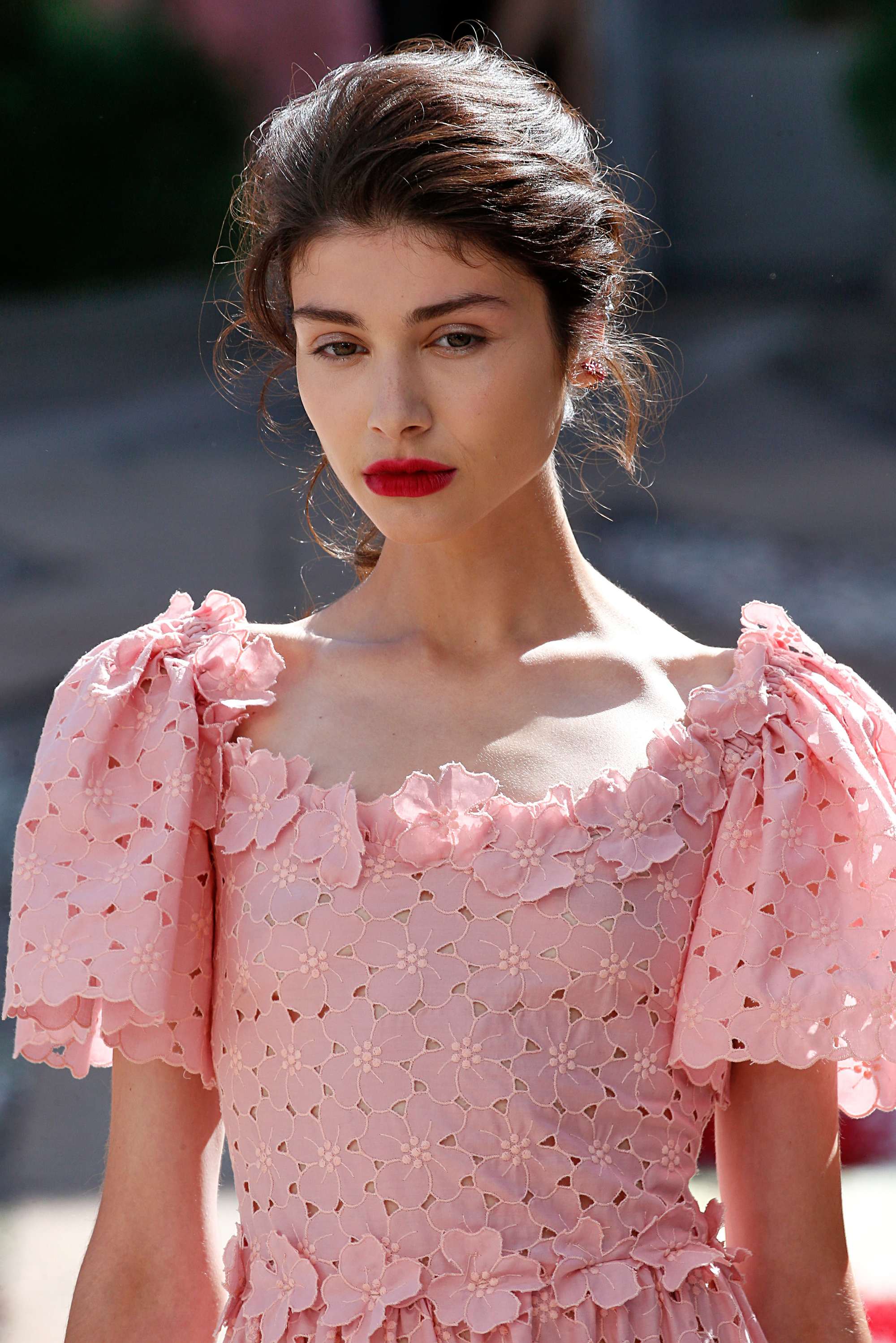 close up shot of model with messy updo hairstyle, wearing all pink and posing outside
