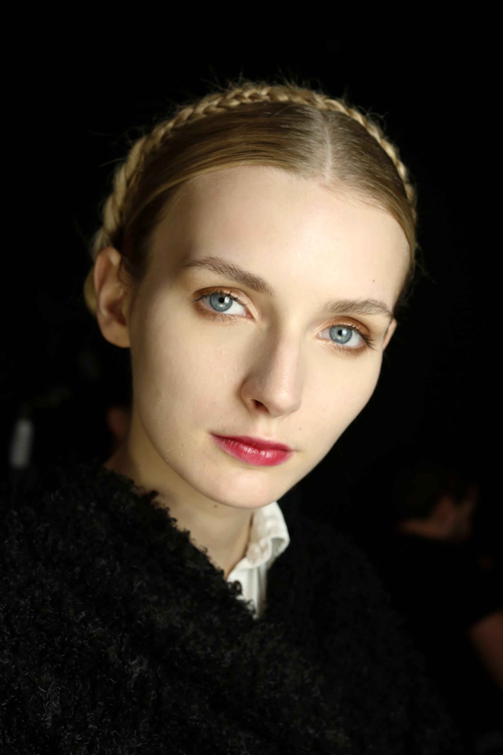 prom hairstyles: close up shot woman with milkmaid braid hairstyle, posing backstage