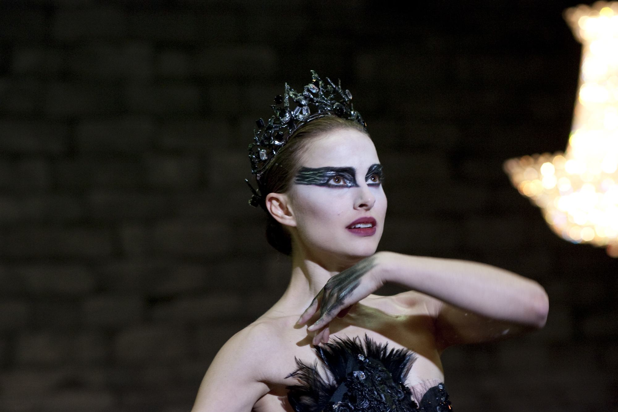 close up shot of natalie portman with tiara and sleek low bun hairstyle, wearing all black with dramatic makeup on the set of black swan