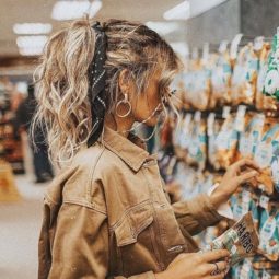 textured hairstyles: close up Instagram shot of woman in a shop, with a messy high ponytail and hair scarf, wearing all tan and sunglasses