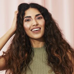 Woman with thick long curly hair touching her head