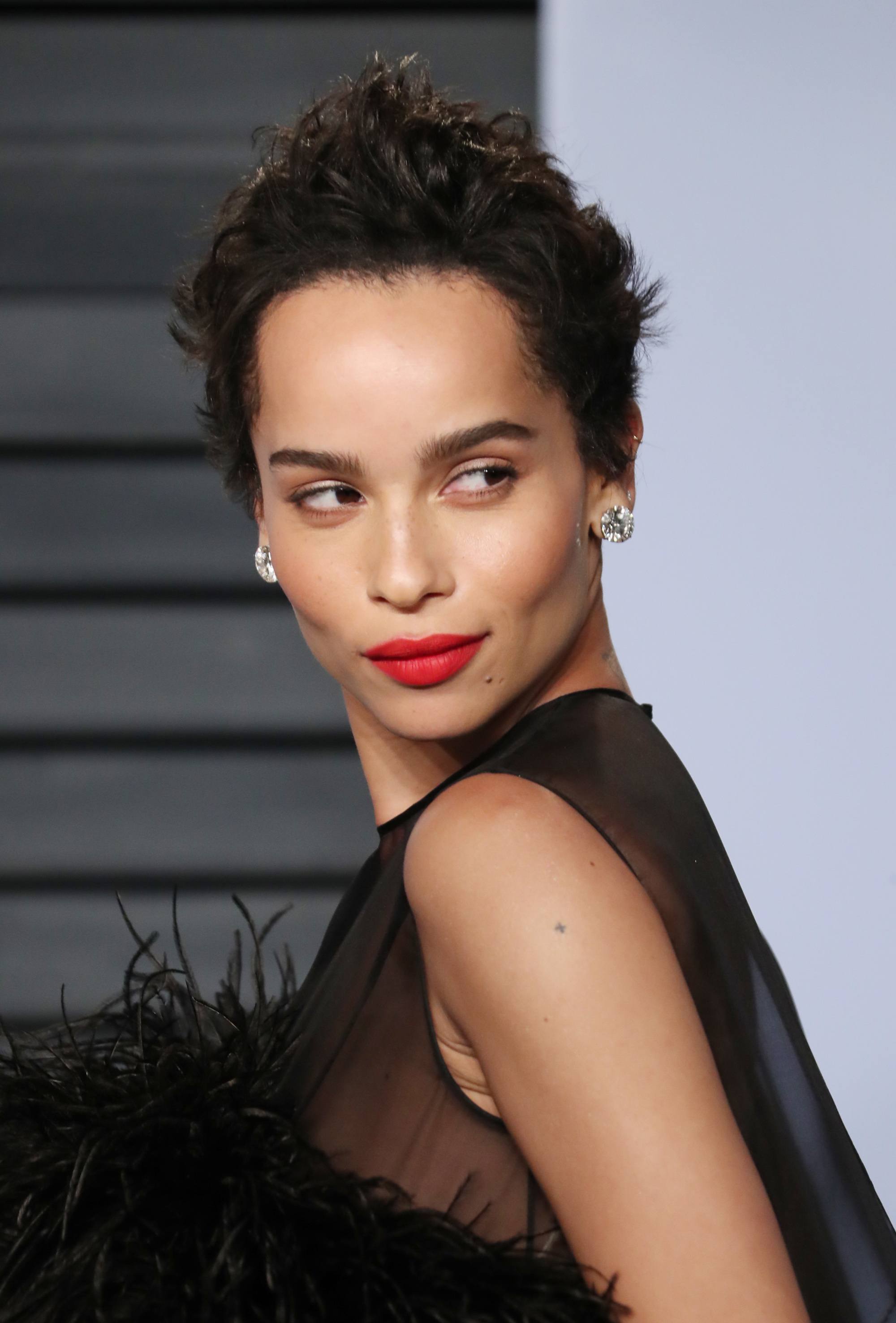 zoe kravitz dark brown spiky pixie cut on red carpet wearing red lipstick and black sheer dress