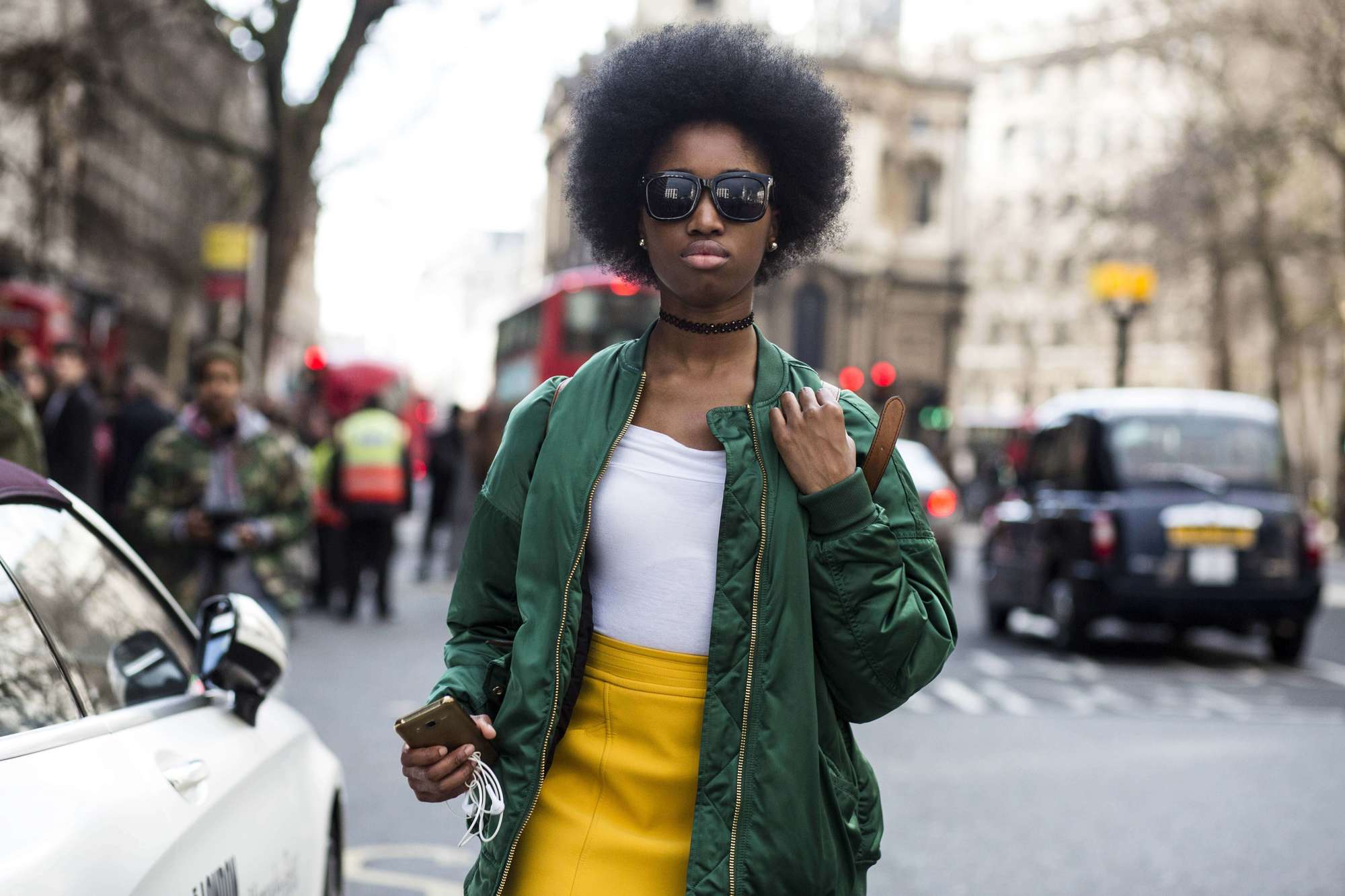 Natural hair wash: afro haired street style model wearing a yellow leather skirt a white top and a green bomber jacket