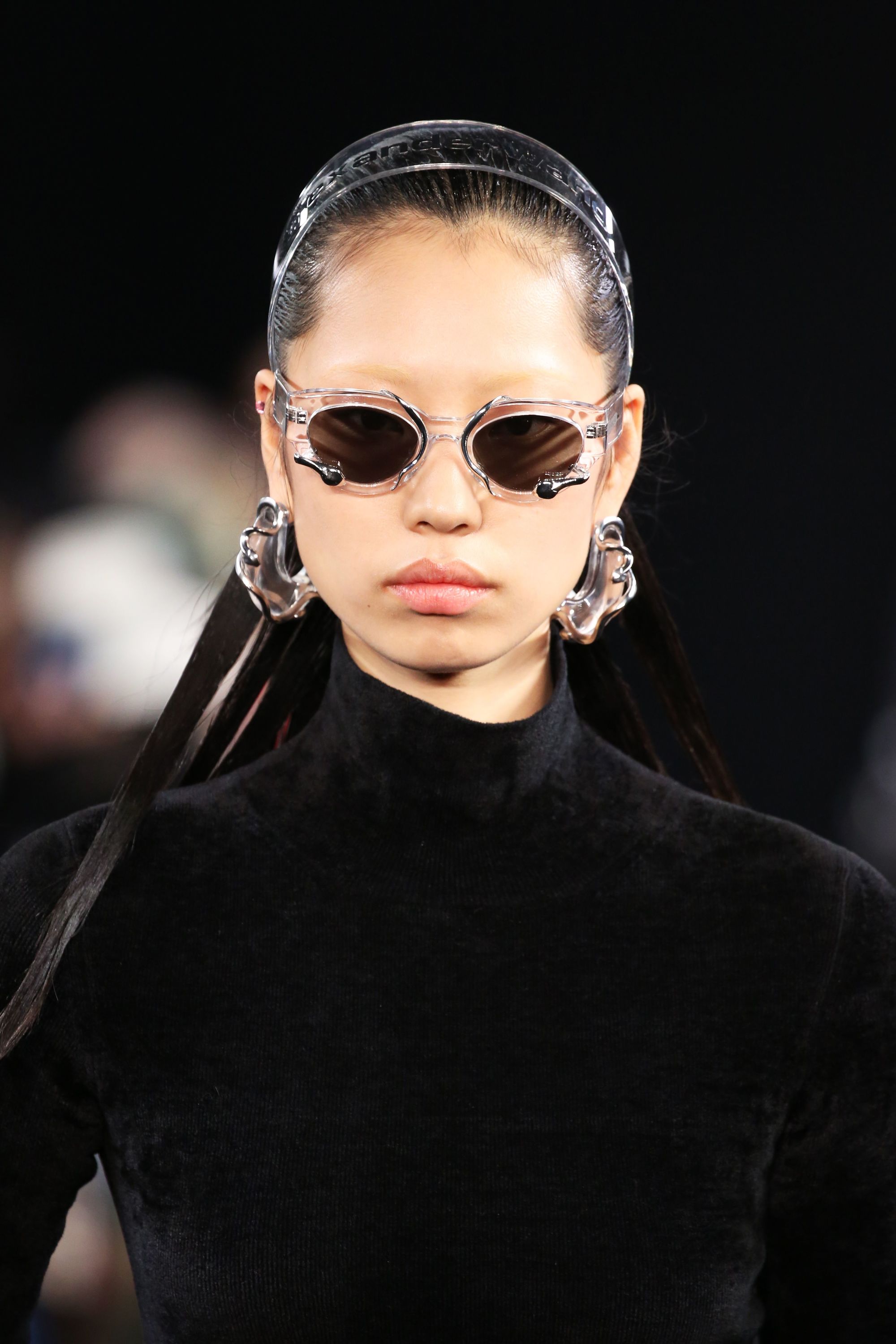 2019 Hair accessories: Model on the runway with a clear alice headband, wearing small glasses and wearing all black