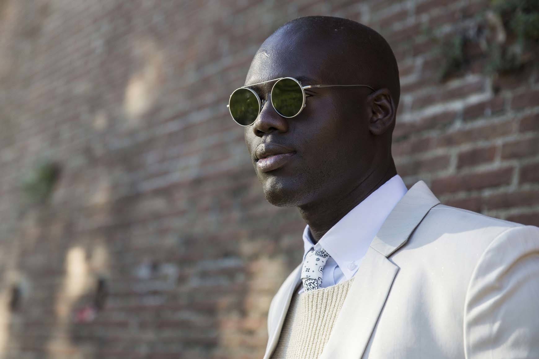 Black man with shaved head and sunglasses outside