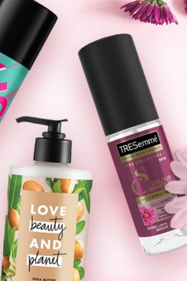 Flat lay shot of the VO5 Flexible Hold Hairspray, Love Beauty & Planet Happy & Hydrated Cleansing Conditioner and TRESemmé Colour Shineplex Serum all things hair